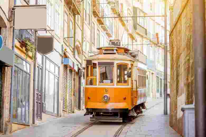 Orange tram going up Portugal's hilly city.